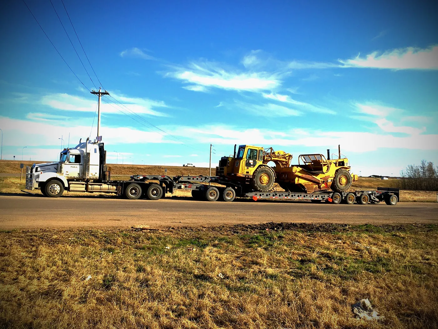Low bed trailer hauling a tracked dozer down a rural Alberta highway